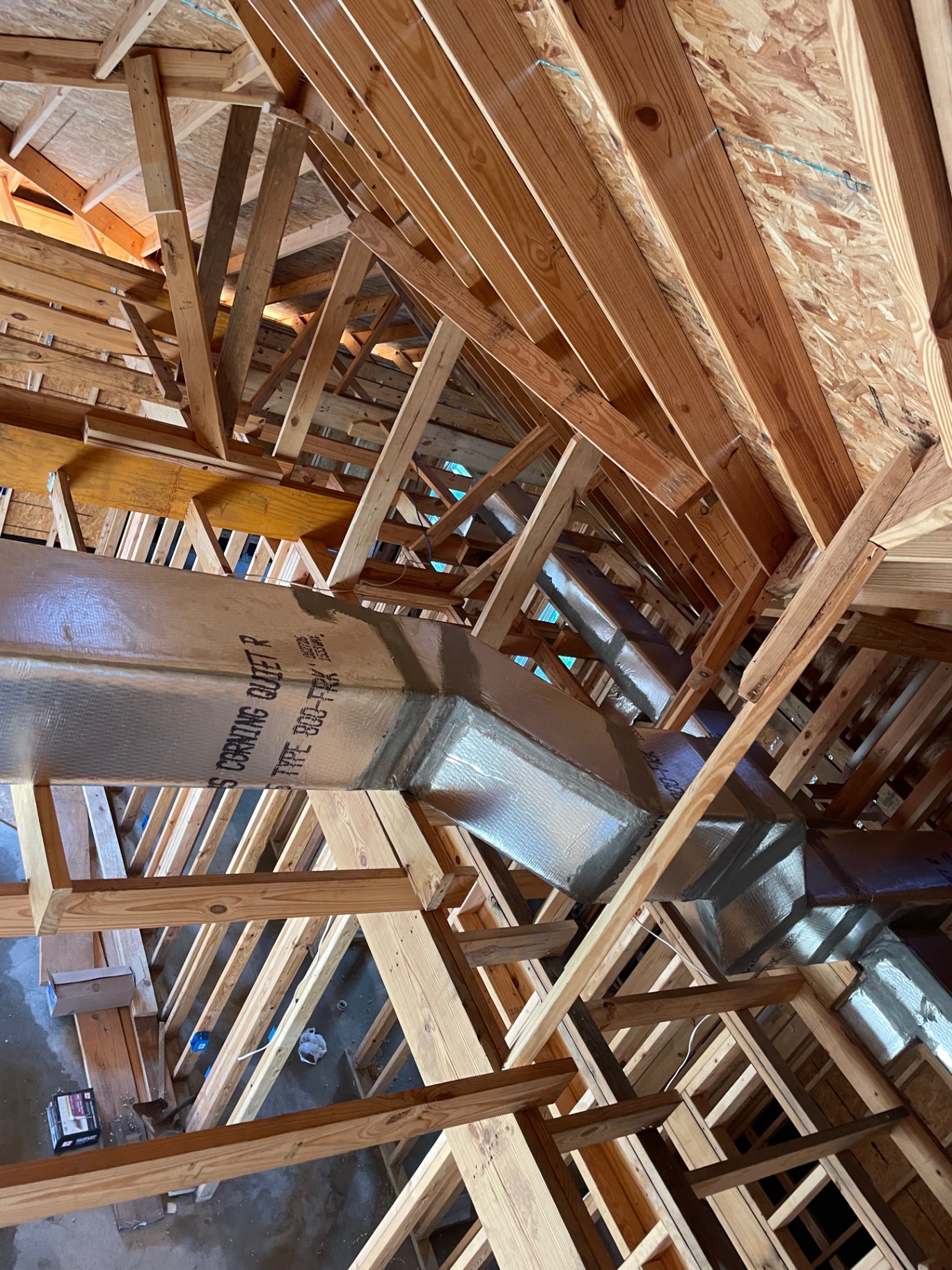 Silver insulated supply plenum and branch runs routed through new roof trusses