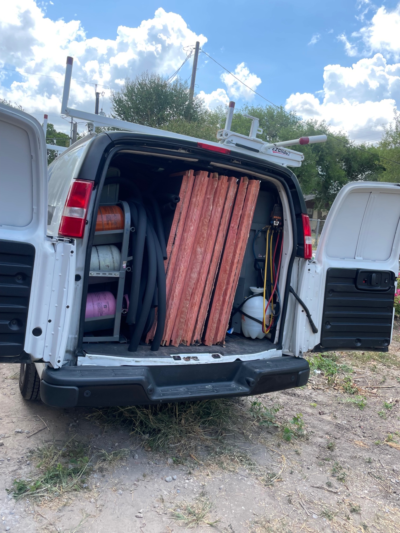 RioTech Services van loaded with refrigerant tanks, gauges, and insulated line set for HVAC calls