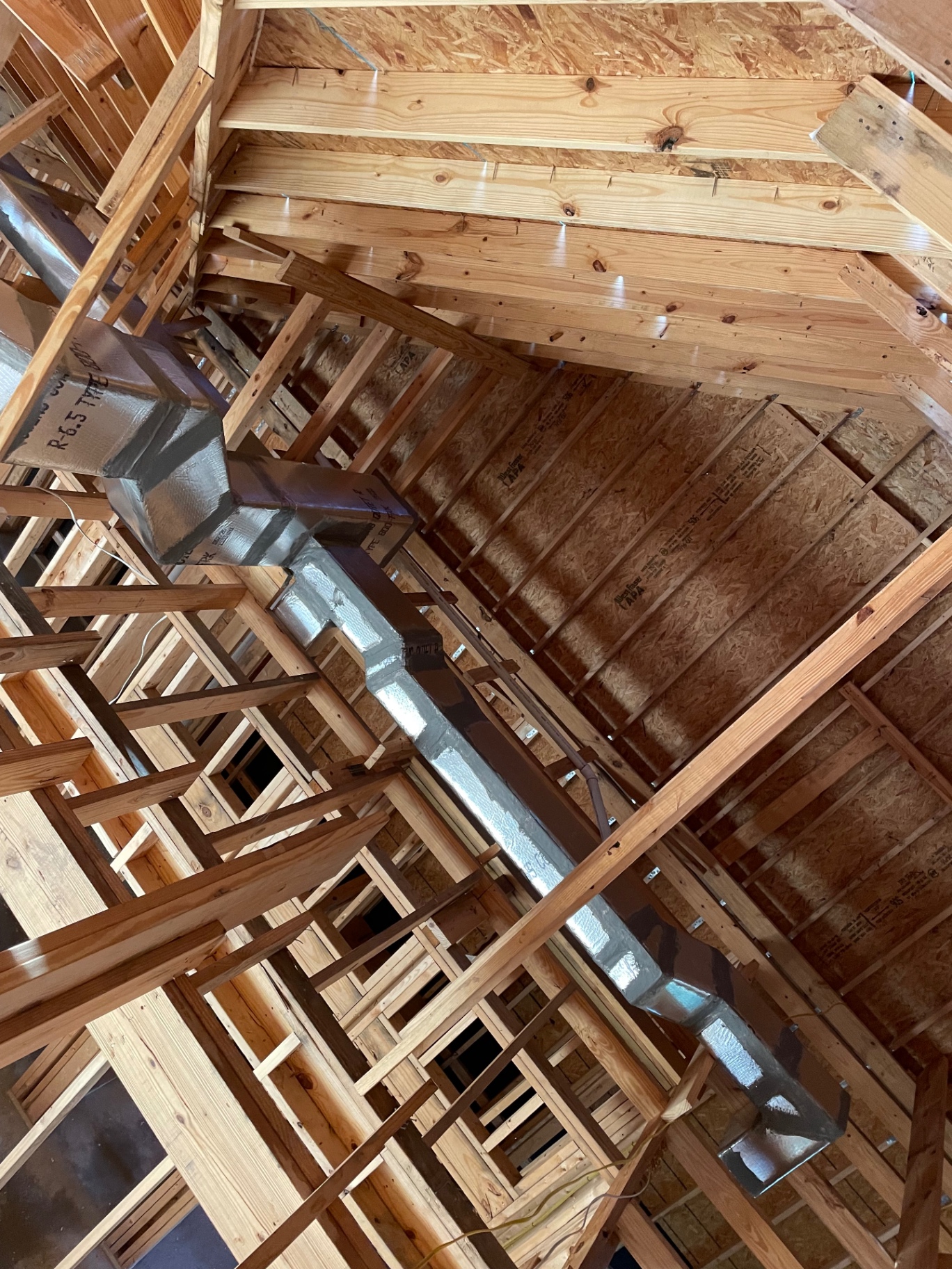Main supply duct with takeoffs feeding multiple rooms in a home under construction